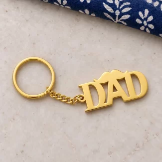 DAD Letter Keychain for Father’s Day in a golden finish, on a light stone display