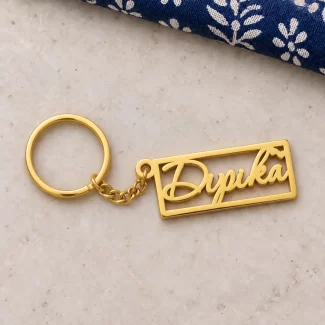 Heart Frame Personalized Name Plate Keychain in a golden finish, on a light stone display