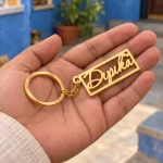 Heart Frame Personalized Name Plate Keychain in a golden finish, held in a hand