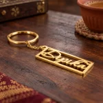 Heart Frame Personalized Name Plate Keychain in a golden finish, on a wooden tabletop
