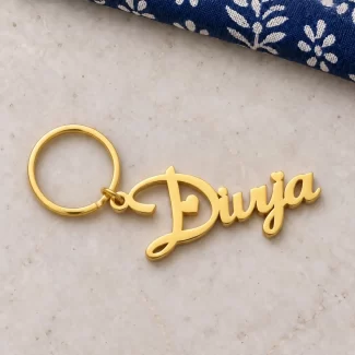 Heart Style Personalized Name Keychain in a golden finish, on a light stone display