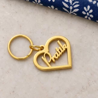 Open Heart Personalized Name Keychain in a golden finish, on a light stone display