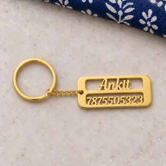 Personalized Name & Number Plate Keychain in a golden finish, on a light stone display