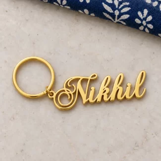 Stylish Personalized Name Keychain in a golden finish, on a light stone display