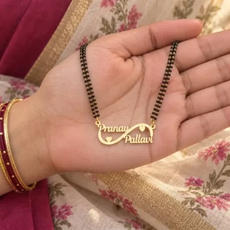 Double Heart Infinity Couple Name Necklace with a black-beaded chain held in a hand