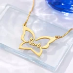 Gold-tone large butterfly outline name necklace on a clear glass display