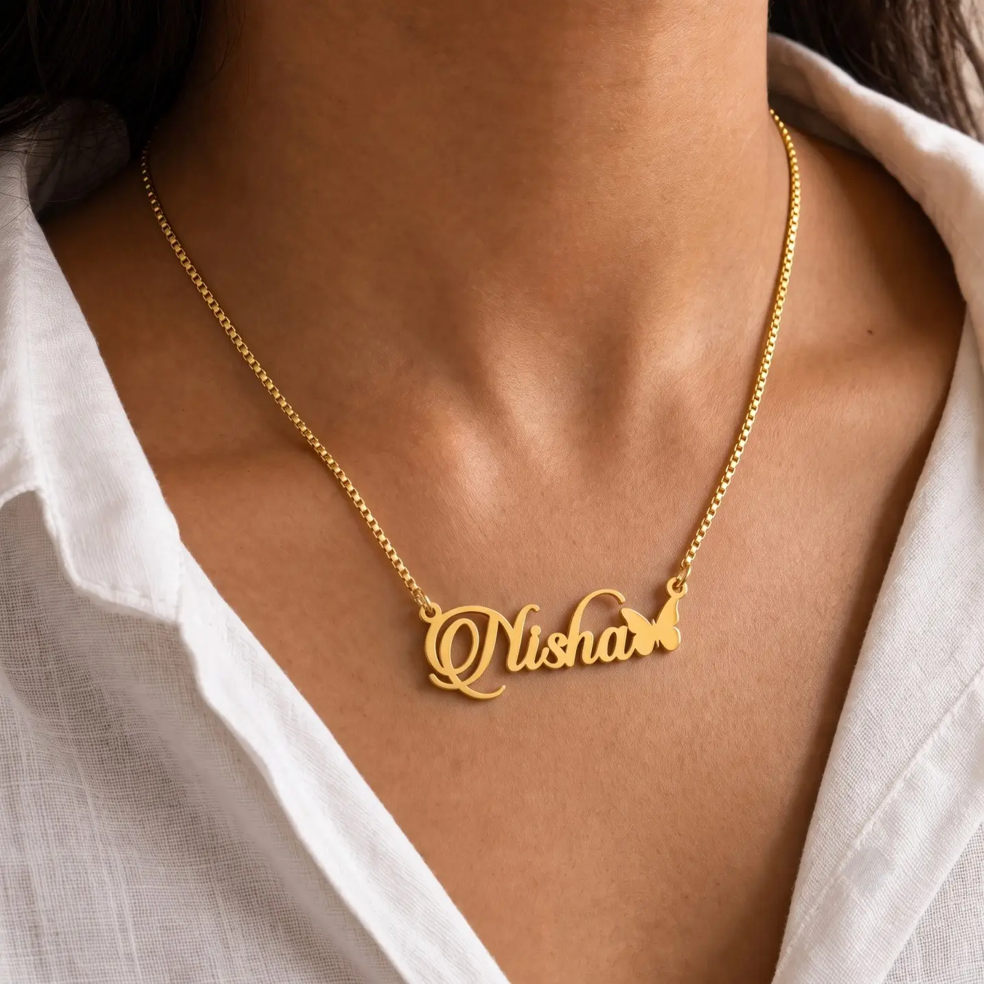 Personalized Butterfly Name Necklace – Worn View Gold-tone script name necklace with a small butterfly worn with a white blouse