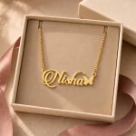 Gold-tone script name necklace with a small butterfly displayed in an open beige jewellery box