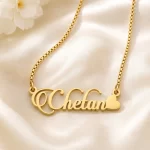 Gold-tone decorative script name necklace with a heart on ivory satin