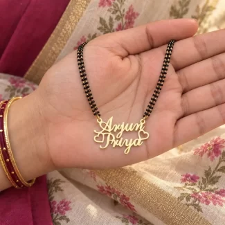 Crown and Heart Couple Name Necklace with a black-beaded chain held in a hand