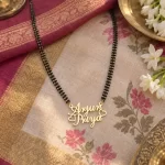 Crown and Heart Couple Name Necklace with a black-beaded chain on floral fabric