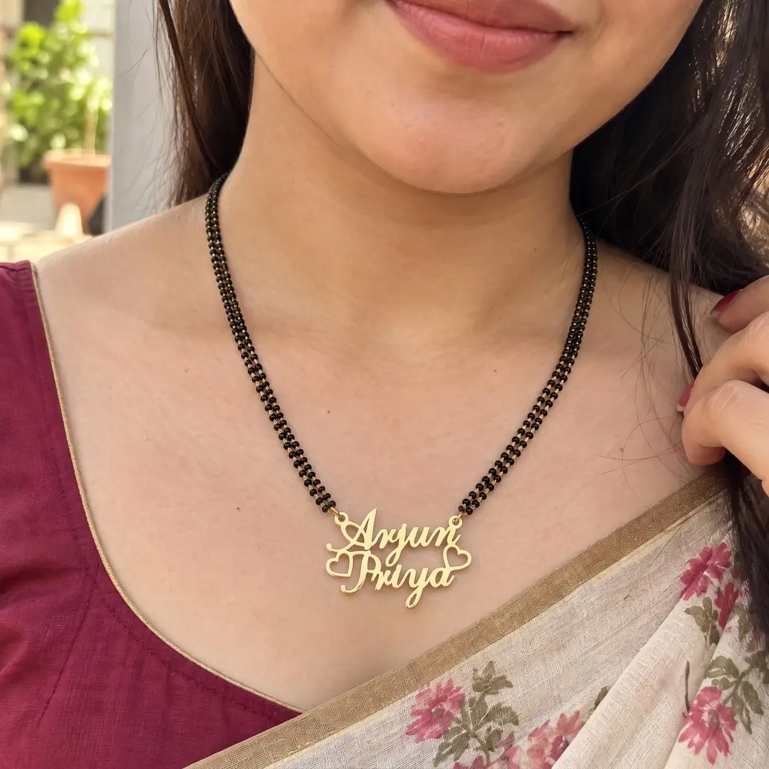 Crown and Heart Couple Name Necklace – With a black-beaded chain worn with a sari Crown and Heart Couple Name Necklace with a black-beaded chain worn with a sari
