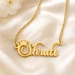 Gold-tone crown name necklace on ivory satin