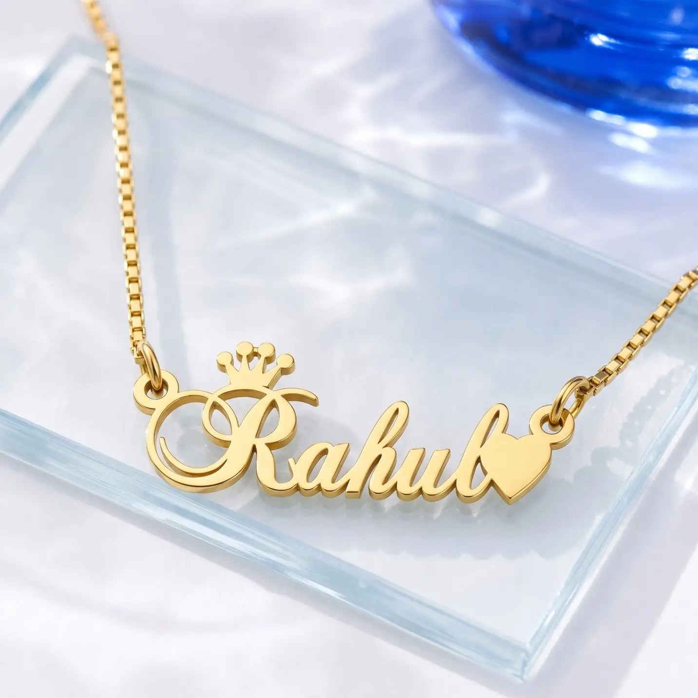 Crown and Heart Name Necklace – Glass Display Gold-tone crown and heart name necklace on a clear glass display