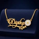 Gold-tone daisy and leaf name necklace on a navy velvet display