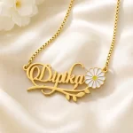 Gold-tone daisy and leaf name necklace on ivory satin
