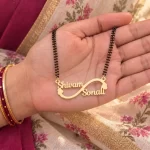 Side Heart Infinity Couple Name Necklace with a black-beaded chain held in a hand