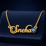 Gold-tone name necklace with a blue evil eye accent on a navy velvet display