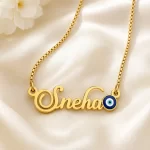 Gold-tone name necklace with a blue evil eye accent on ivory satin