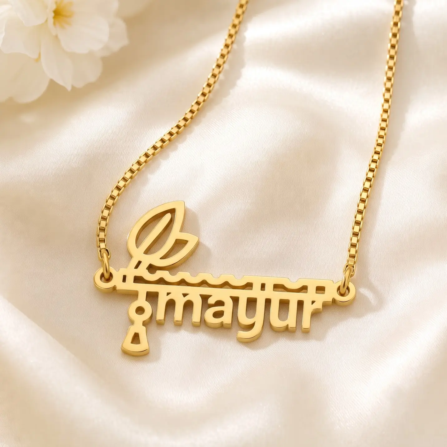 Flute and Feather Name Pendant – Satin Detail Gold-tone flute and feather name pendant on ivory satin