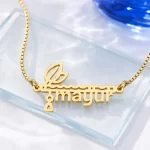 Gold-tone flute and feather name pendant on a clear glass display