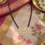 Half Heart Couple Name Necklace with a black-beaded chain on floral fabric