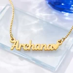 Gold-tone simple name pendant with a small heart on a clear glass display
