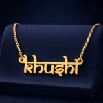 Gold-tone Indian style name necklace on a navy velvet display