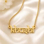 Gold-tone Indian style name necklace on ivory satin