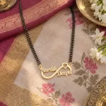 Infinity Heart Couple Name Mangalsutra Pendant with a black-beaded chain on floral fabric