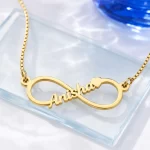 Gold-tone infinity outline name necklace on a clear glass display