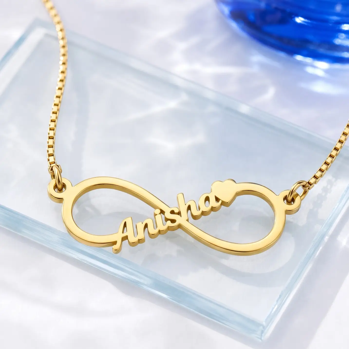 Personalized Infinity Name Necklace – Glass Display Gold-tone infinity outline name necklace on a clear glass display