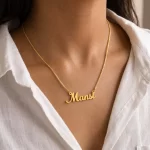 Gold-tone simple script name necklace worn with a white blouse