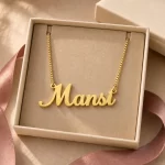 Gold-tone simple script name necklace displayed in an open beige jewellery box